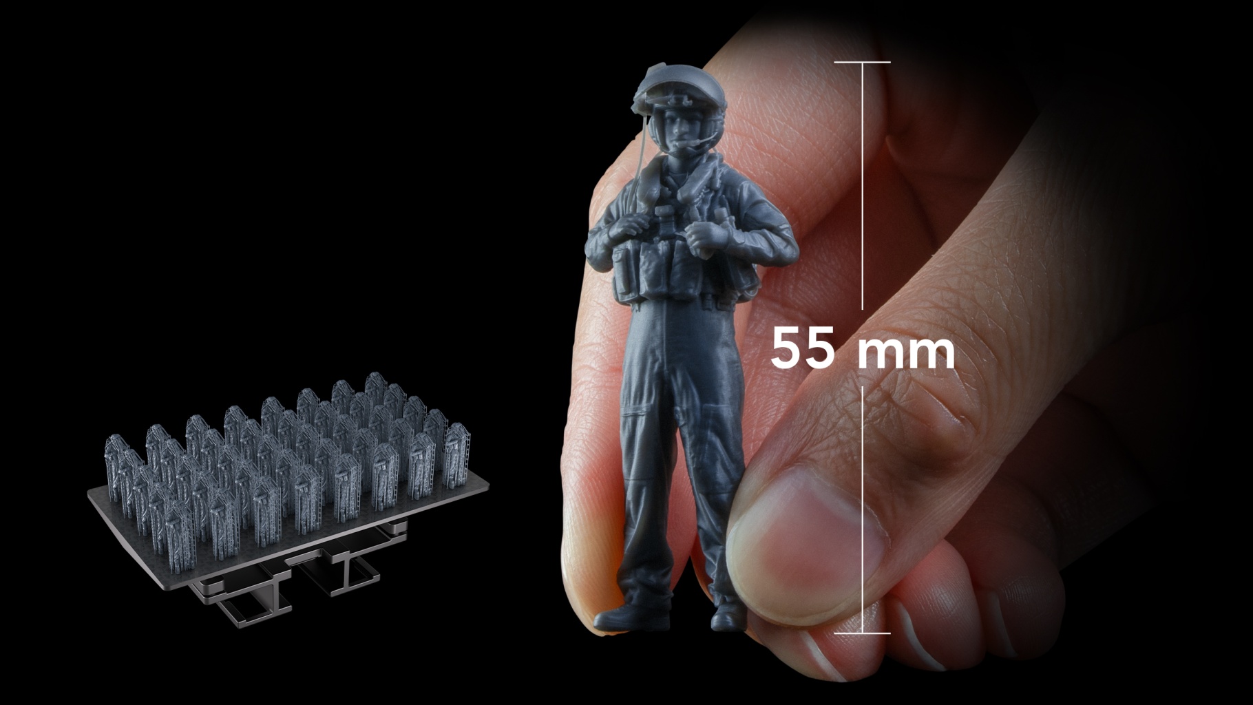 55 mm detailed miniature soldier held between fingers beside a full build plate of miniatures, showcasing fine-detail batch printing.